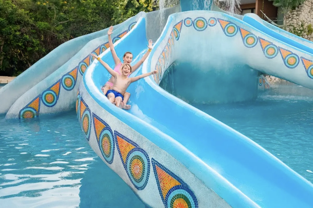 Hotel Xcaret Mexico kids riding down slide at one of the best Riviera Maya Resorts for Familiies